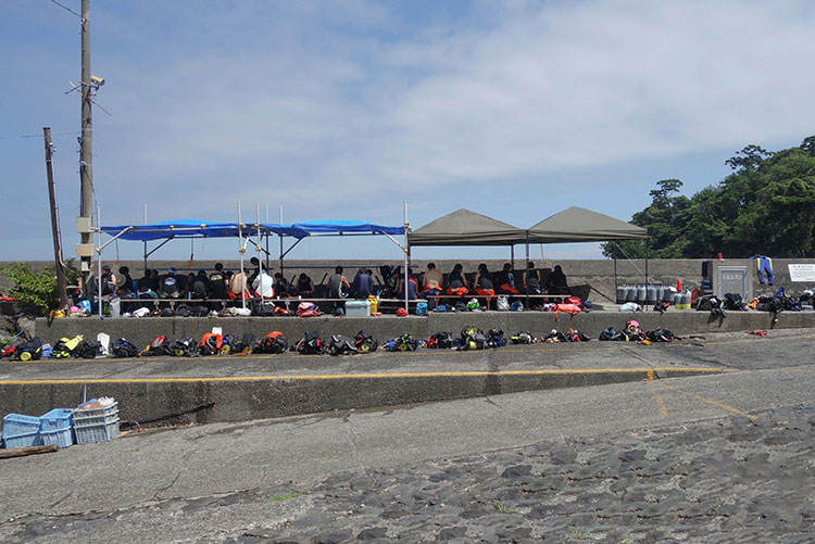 防波堤の段々を利用した仮設の休憩空間。整然と並ぶダイビング用品。